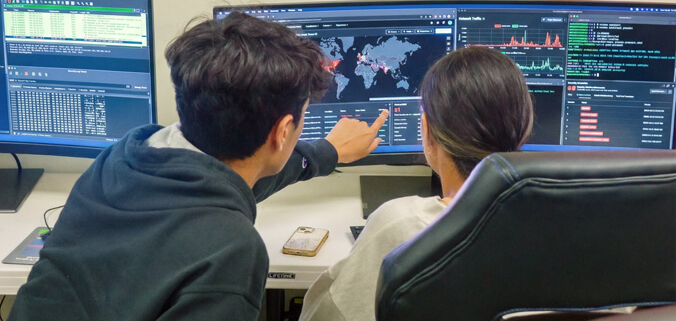 Cyber Security - two people in front of a monitor