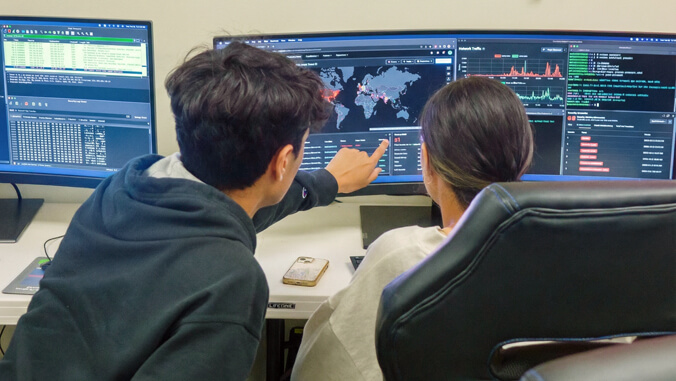 Cyber Security - two people in front of a monitor
